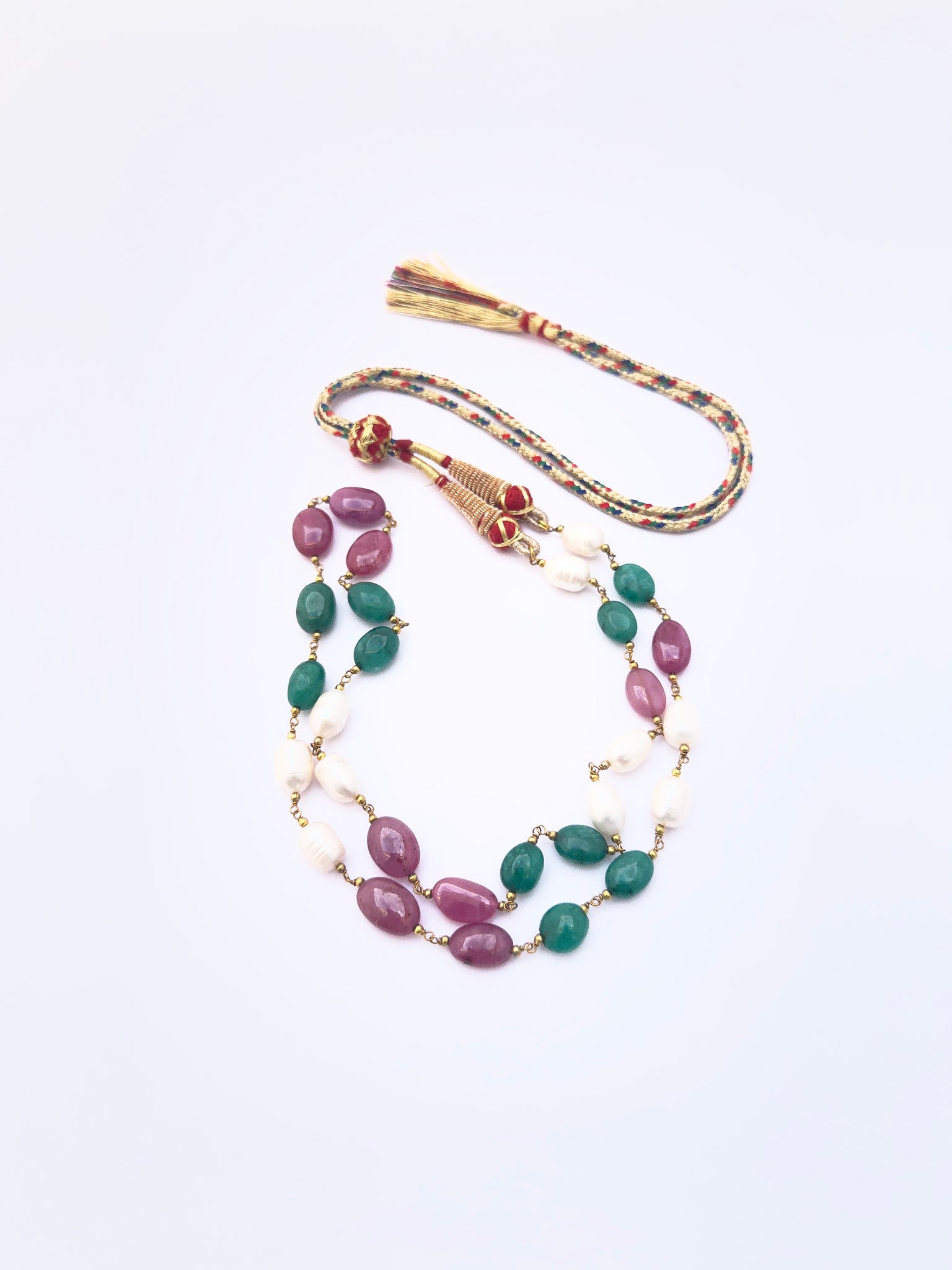 Detailed view of emerald and ruby beads alongside lustrous pearls, polished oval cut arrangement.