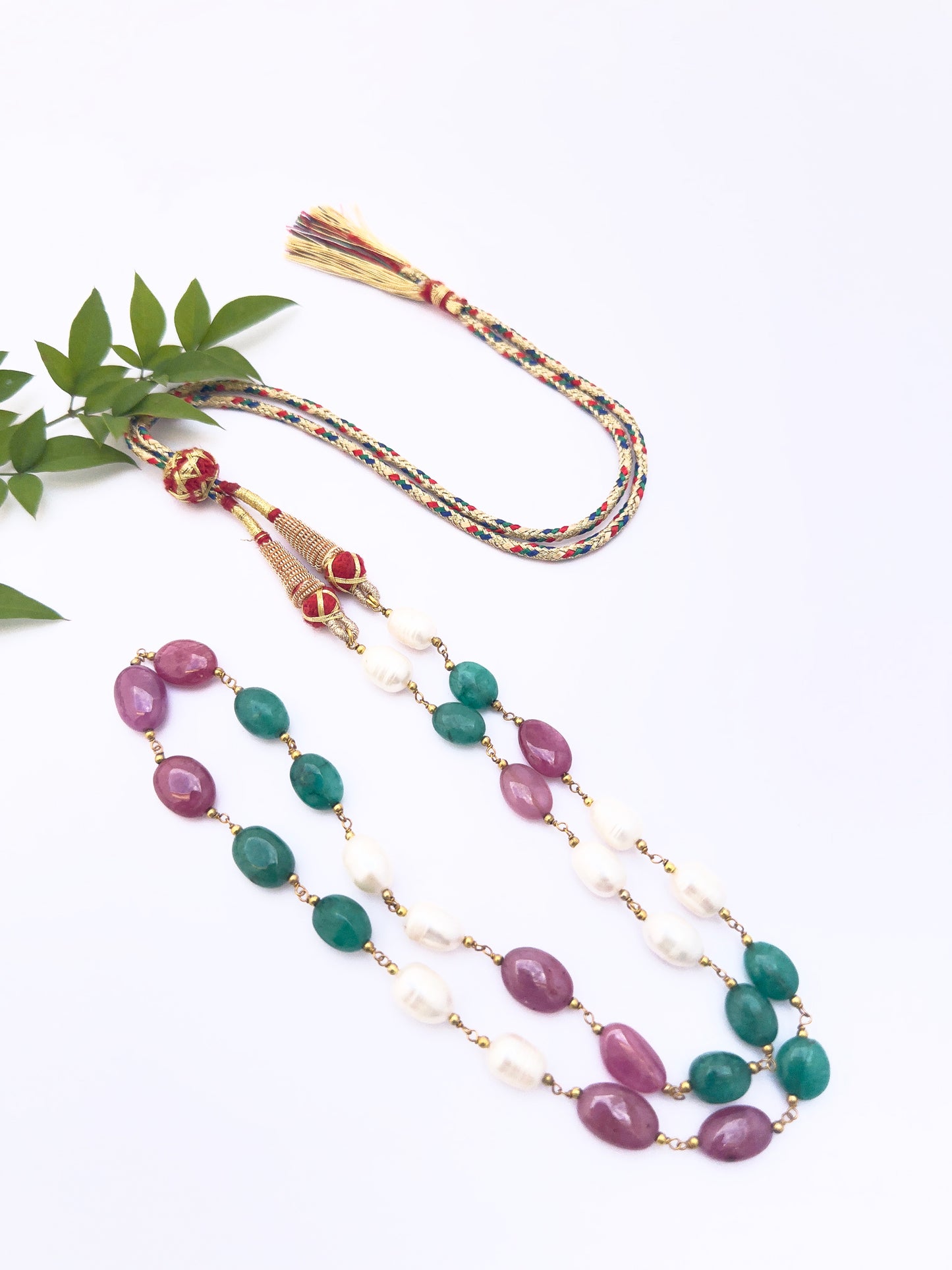 Necklace highlighting natural gemstones in oval cut, colourful contrast of pearls, emeralds, and rubies.
