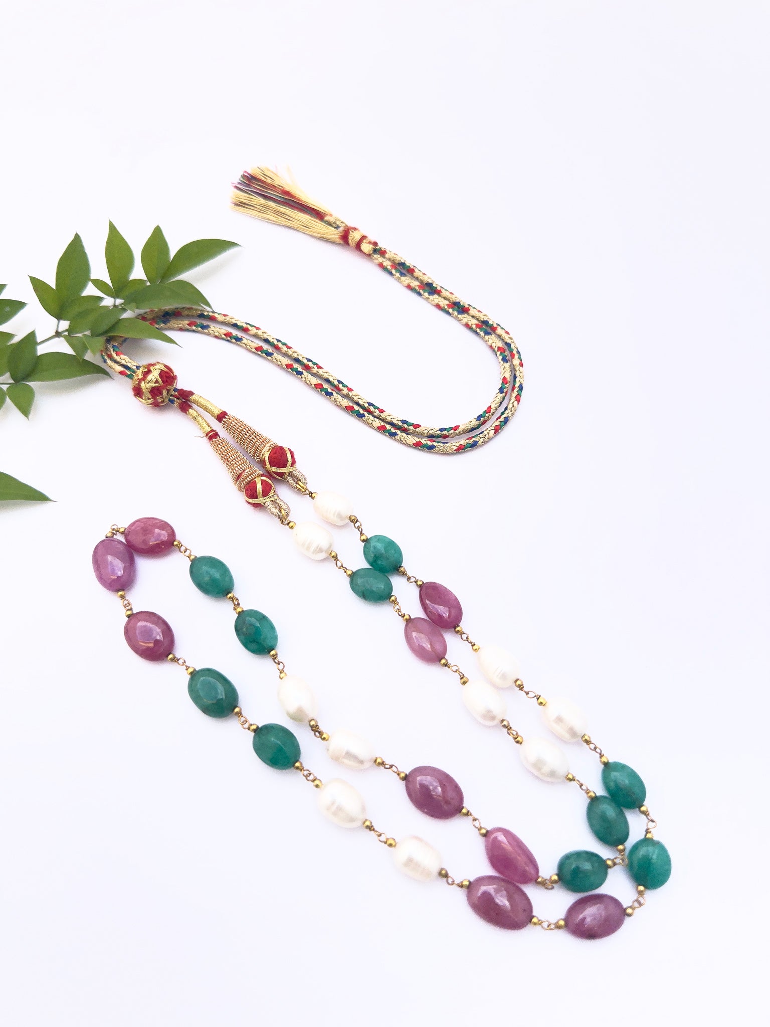 Necklace highlighting natural gemstones in oval cut, colourful contrast of pearls, emeralds, and rubies.