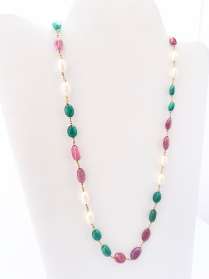 Multi precious strand necklace showcasing vibrant green emeralds, deep red rubies, and glowing pearls.