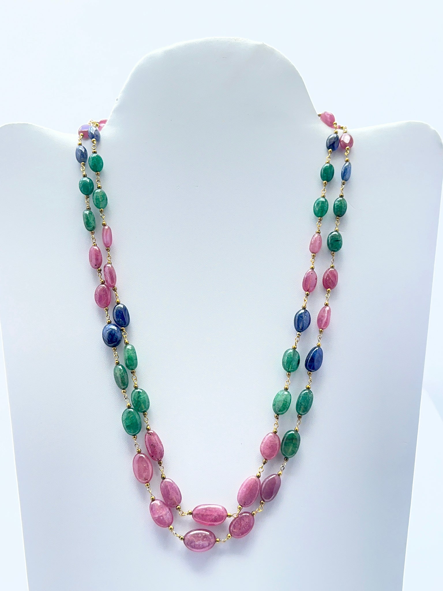Close‑up of polished oval gemstone beads arranged on a finished multi‑gem necklace.
