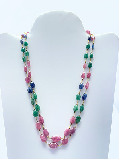 Close‑up of polished oval gemstone beads arranged on a finished multi‑gem necklace.