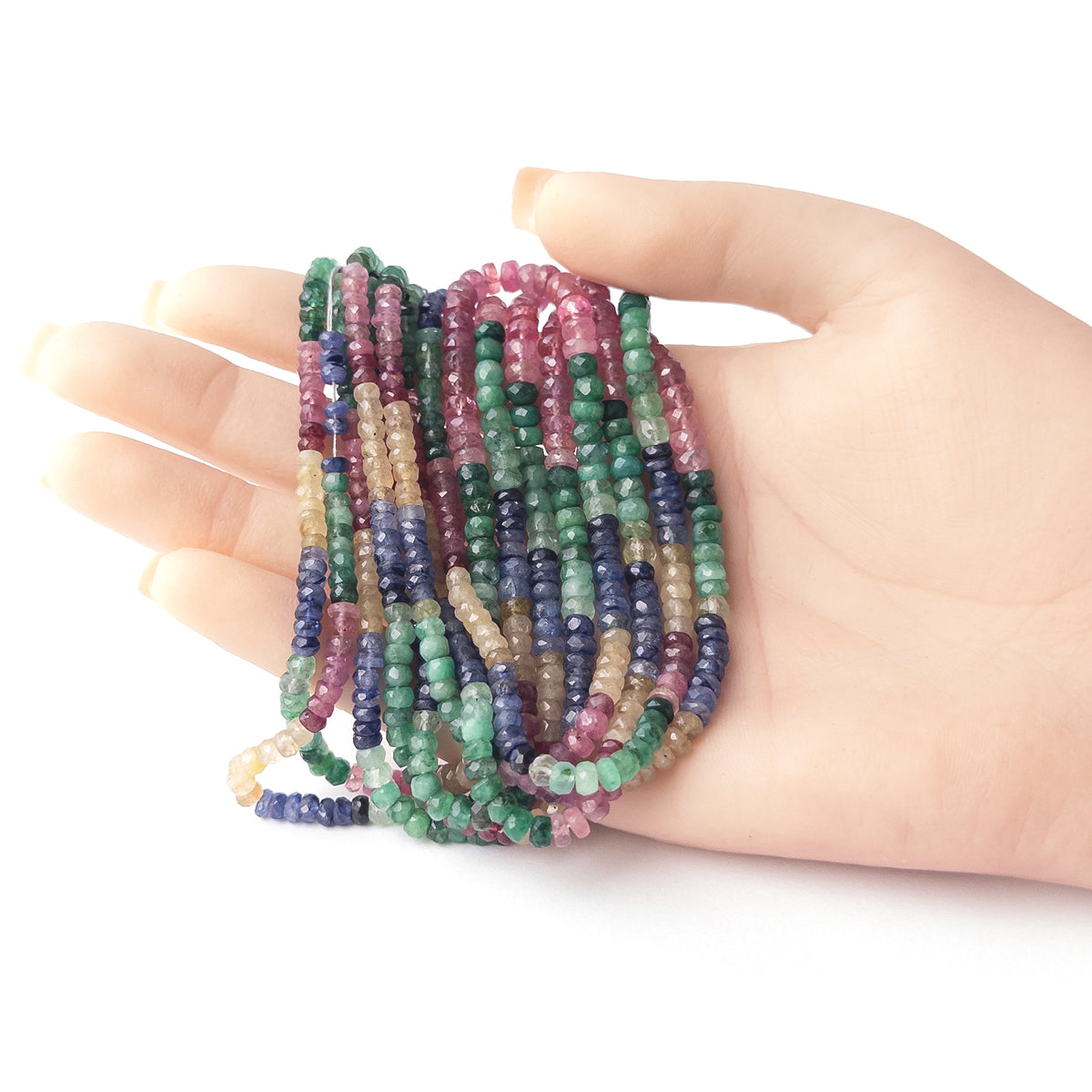 A person holds delicate strands of Multi Precious Ruby Blue Sapphire Yellow Sapphire and Emerald beads, showcasing their faceted rondelle design.