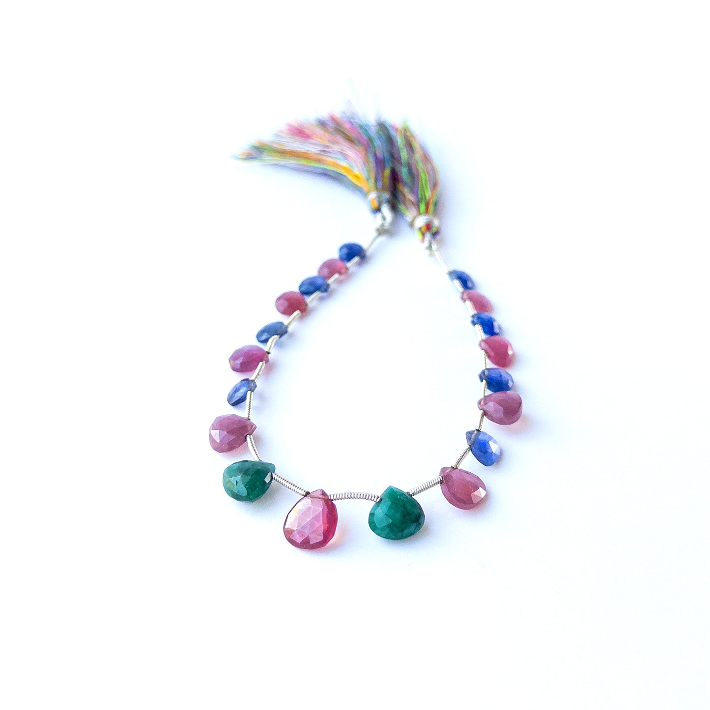 Mixed Ruby, Blue Sapphire and Emerald briolette beads arranged together showing bright gemstone contrast.