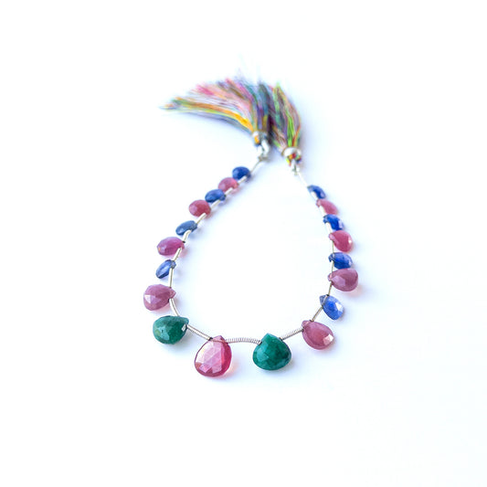 Mixed Ruby, Blue Sapphire and Emerald briolette beads arranged together showing bright gemstone contrast.