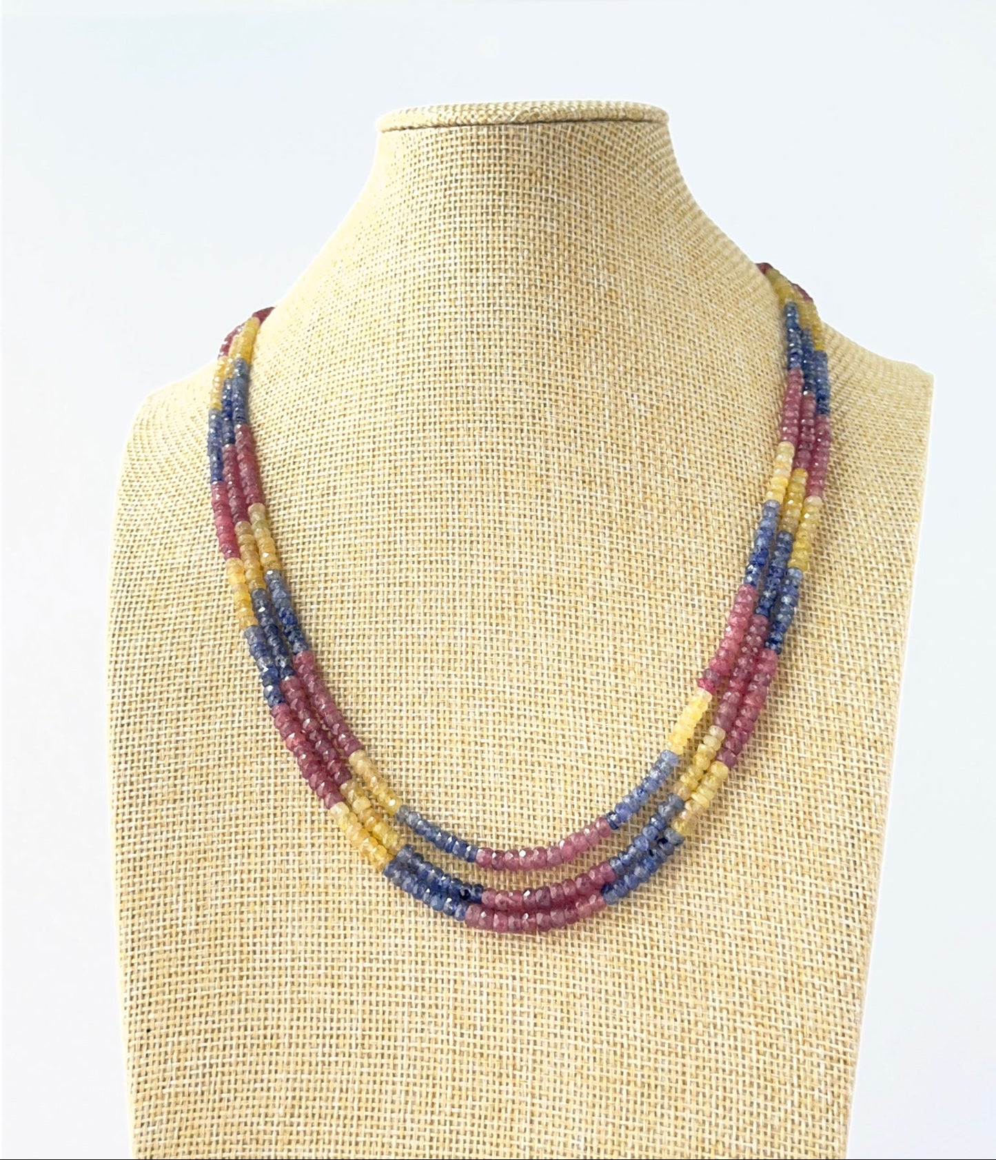 Three‑strand multi‑precious necklace featuring faceted rondelle ruby, blue sapphire, and yellow sapphire beads sized 4–4.5mm.
