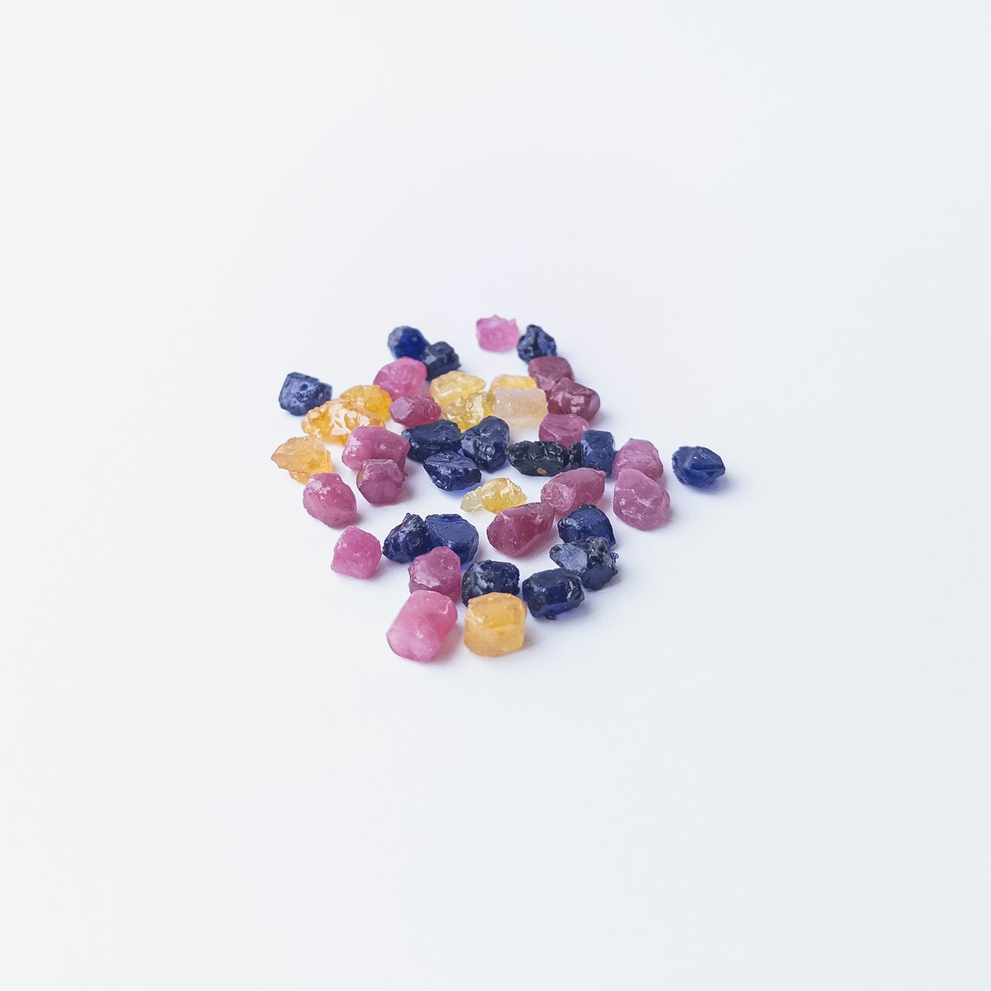 Mixed Ruby, Blue Sapphire and Yellow Sapphire rough stones arranged together showing vivid colour contrast.