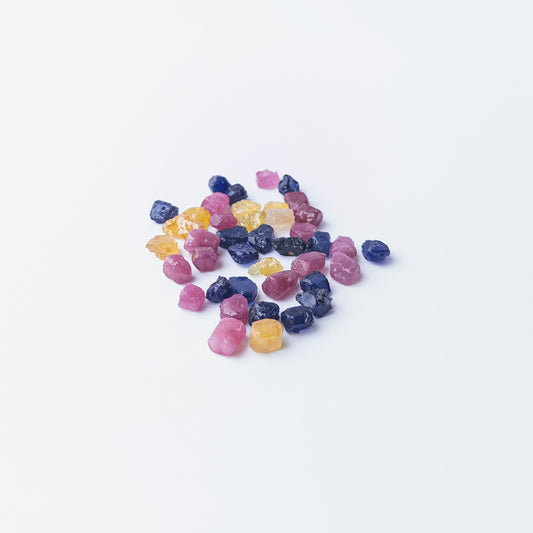 Mixed Ruby, Blue Sapphire and Yellow Sapphire rough stones arranged together showing vivid colour contrast.