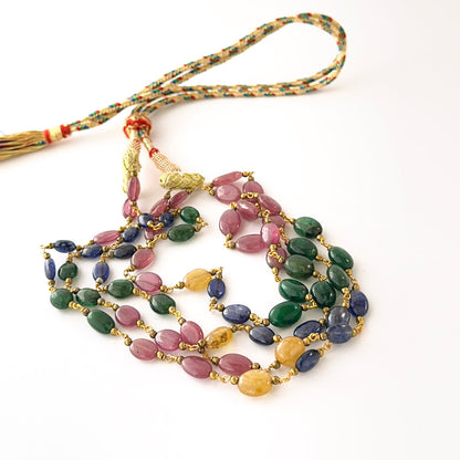Two‑layer ruby, sapphire, and emerald necklace featuring smooth oval beads and adjustable length.