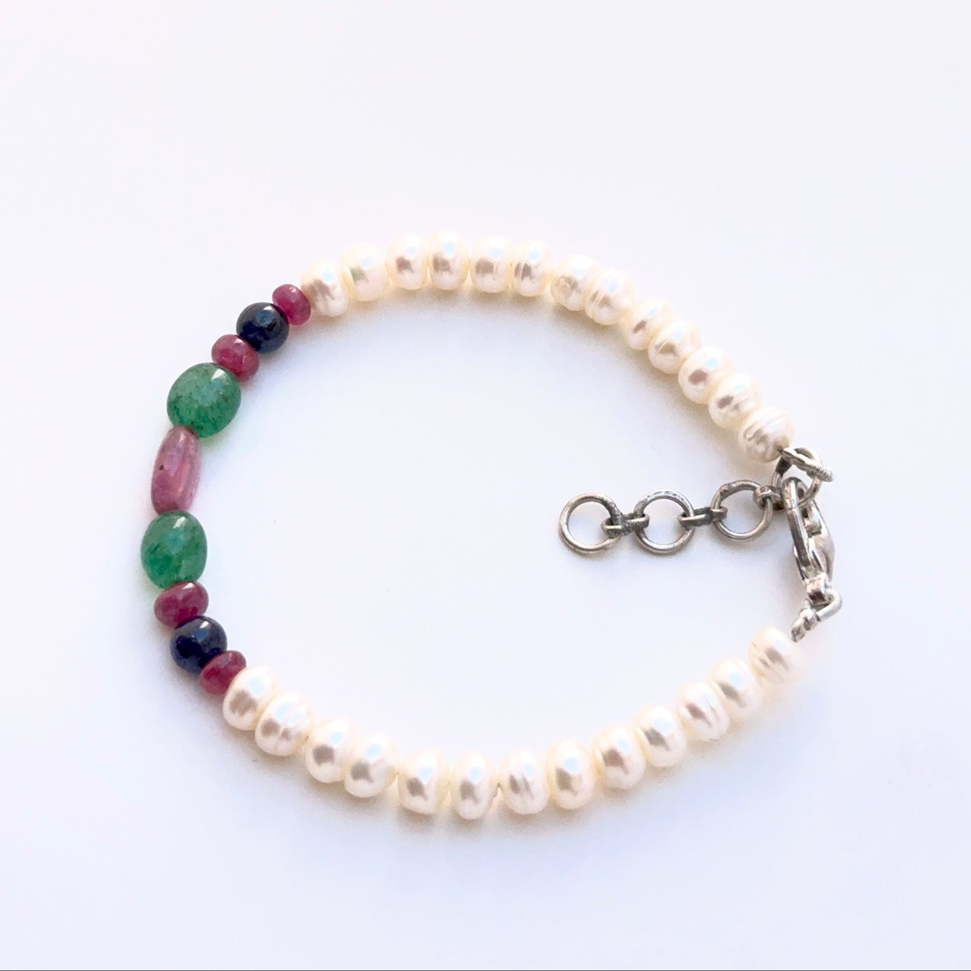 Elegant bracelet featuring ruby, emerald, sapphire and pearls in a refined layout.