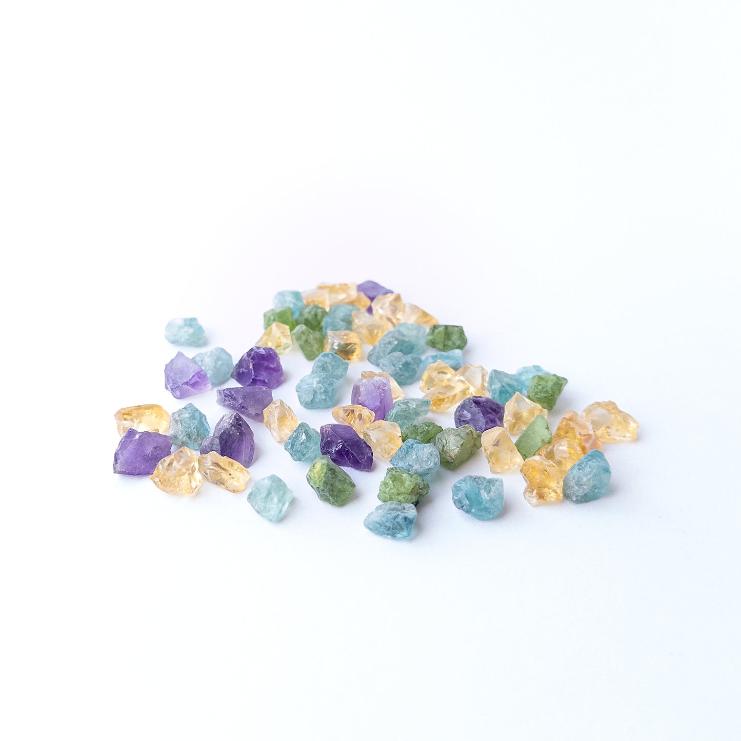 Mixed Amethyst, Citrine, Apatite and Peridot rough stones arranged together showing vivid colour contrast.