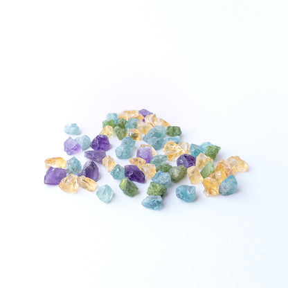 Mixed Amethyst, Citrine, Apatite and Peridot rough stones arranged together showing vivid colour contrast.