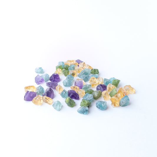 Mixed Amethyst, Citrine, Apatite and Peridot rough stones arranged together showing vivid colour contrast.