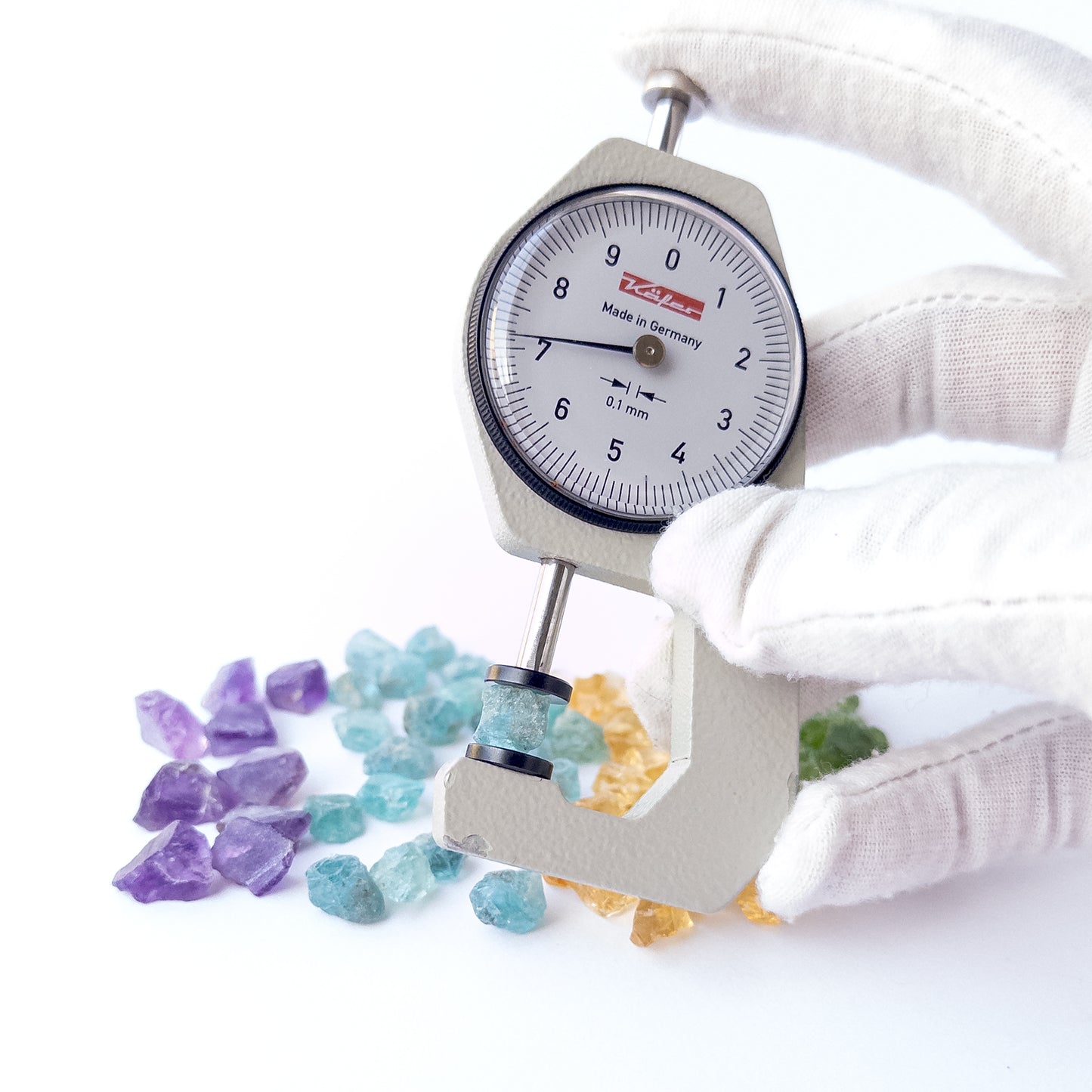 A dial gauge measures the Amethyst, Citrine, Apatite and Peridot rough 7–8mm gemstone.