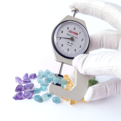 A dial gauge measures the Amethyst, Citrine, Apatite and Peridot rough 7–8mm gemstone.