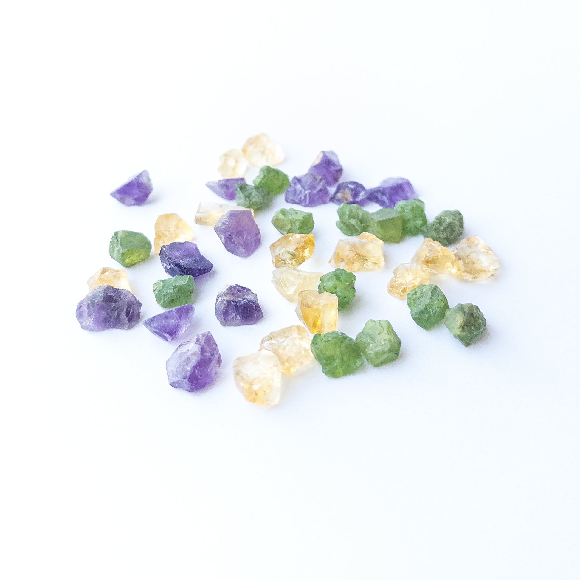 Mixed Amethyst, Citrine and Peridot rough stones arranged together showing vivid colour contrast.