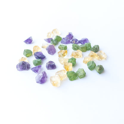 Mixed Amethyst, Citrine and Peridot rough stones arranged together showing vivid colour contrast.