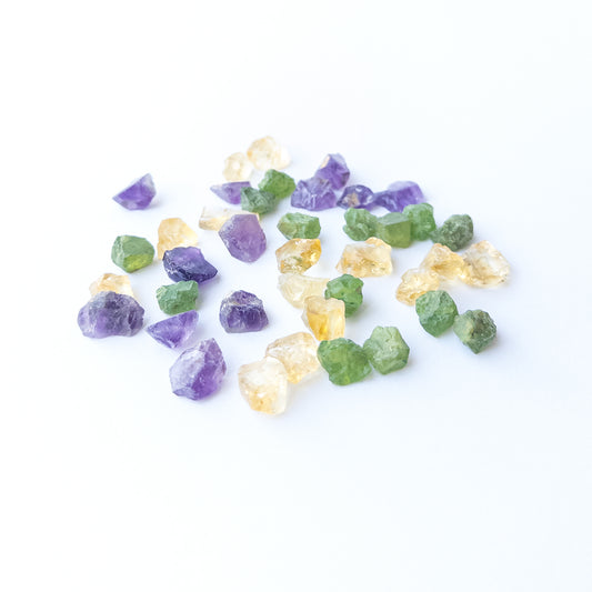 Mixed Amethyst, Citrine and Peridot rough stones arranged together showing vivid colour contrast.