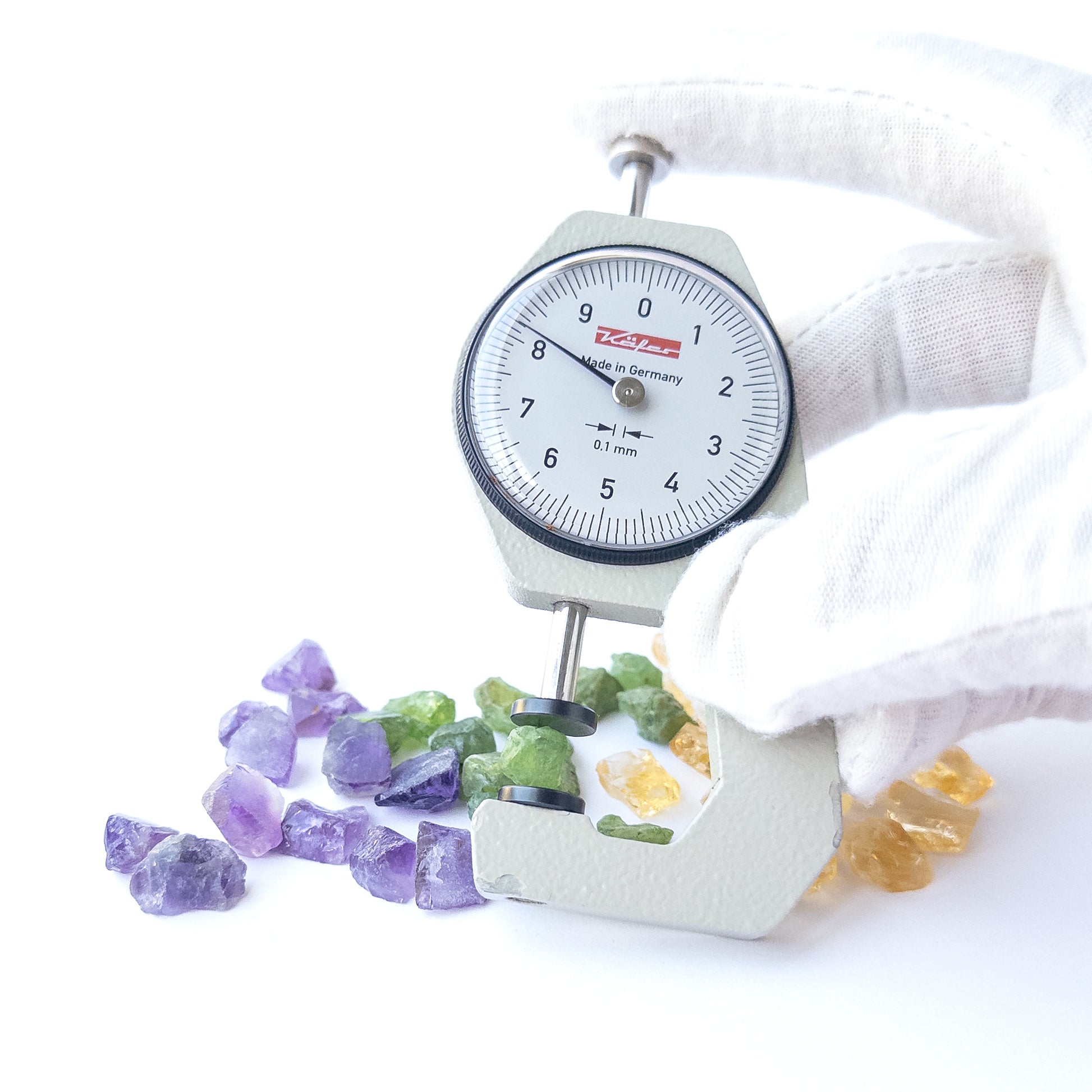 A dial gauge measures the Amethyst, Citrine and Peridot rough 6–8mm gemstone.
