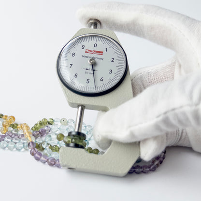 A dial gauge measures the multi stone smooth round 4.5–4.7mm gemstone.