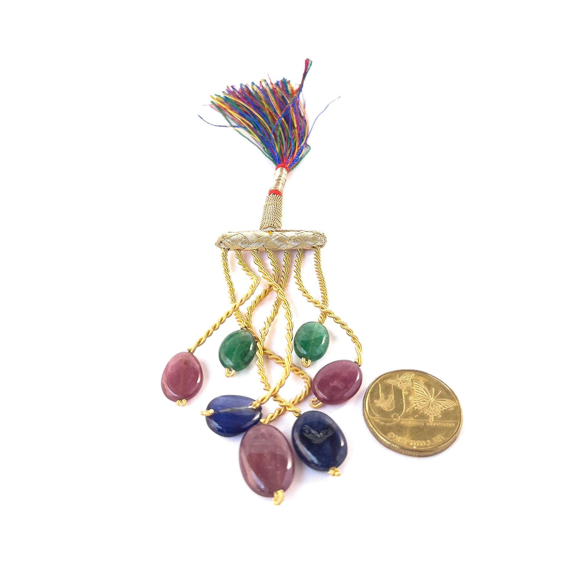 A coin is placed near delicate pieces of Emerald, Ruby and Sapphire smooth oval beads for scale.