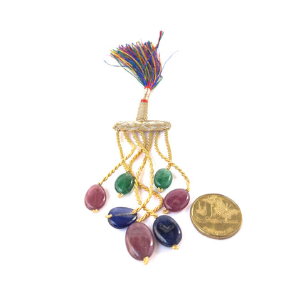 A coin is placed near delicate pieces of Emerald, Ruby and Sapphire smooth oval beads for scale.