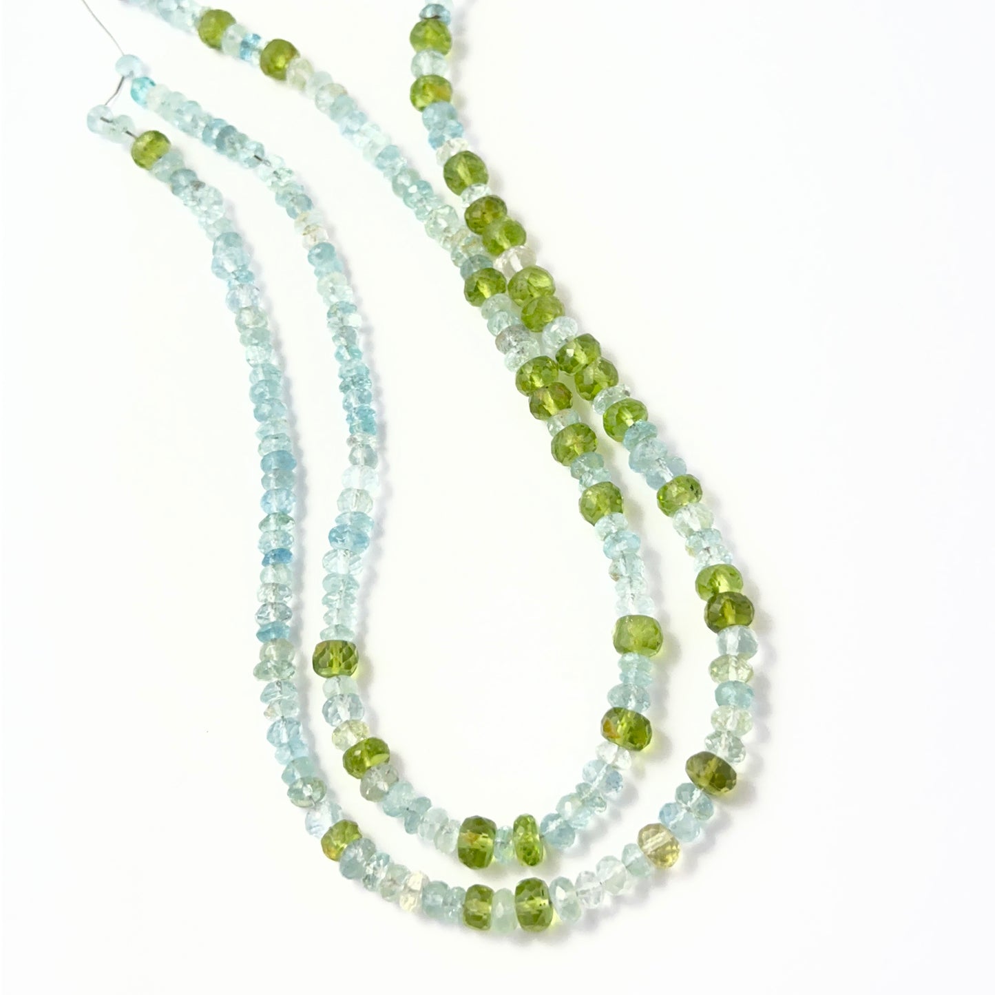 Close view of Peridot and Aquamarine faceted rondelles arranged on a 29cm strand for handmade jewellery components.