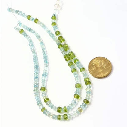 A coin is place near delicate strands of Peridot and Aquamarine beads for scale.