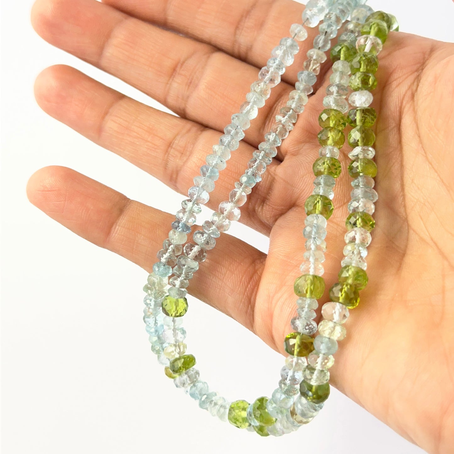 Mixed Peridot and Aquamarine faceted rondelles aligned on a strand, highlighting clarity, colour and quality stone beads.