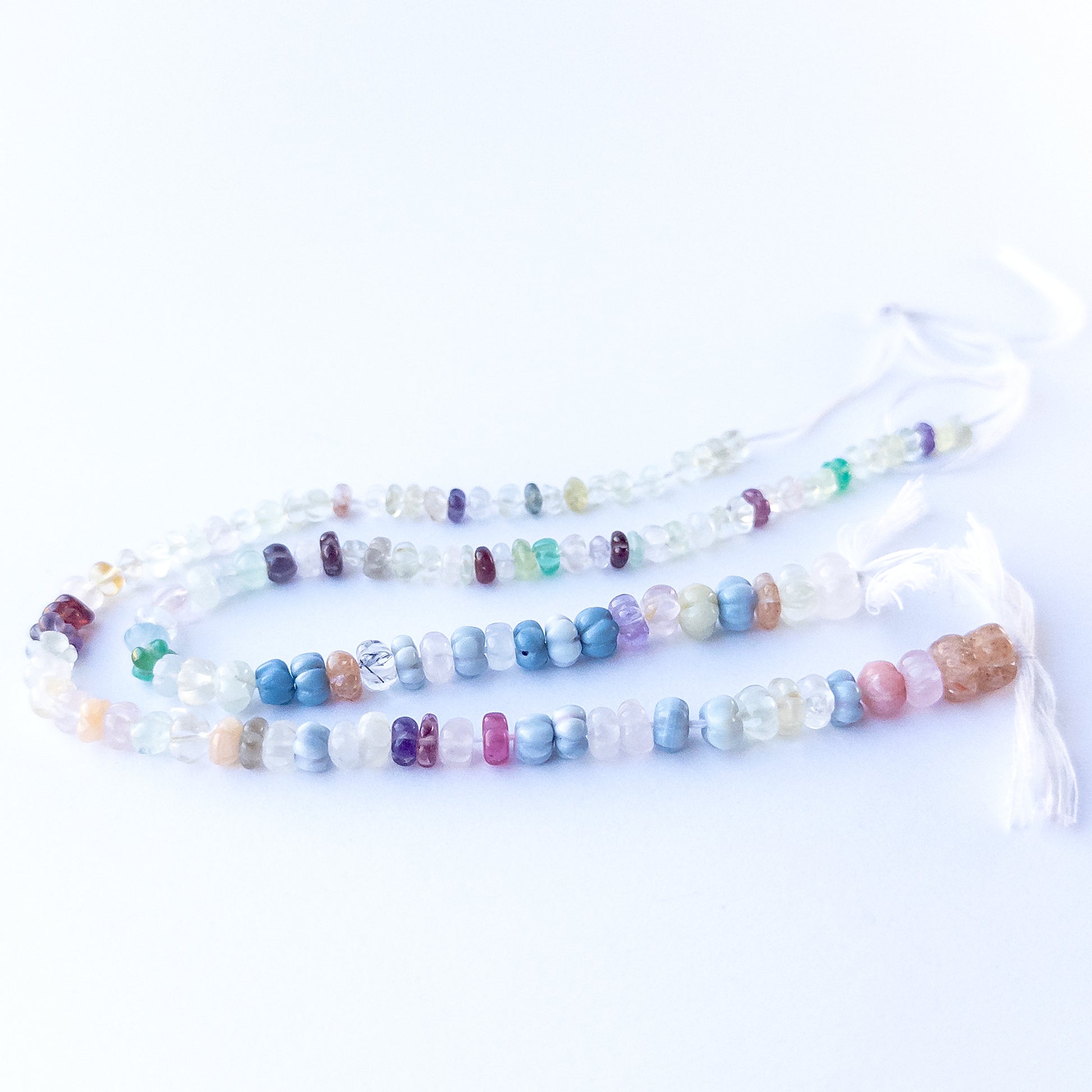 Close‑up of authentic multi‑stone pumpkin cut beads highlighting their shine, carved texture and mixed gemstone colours.