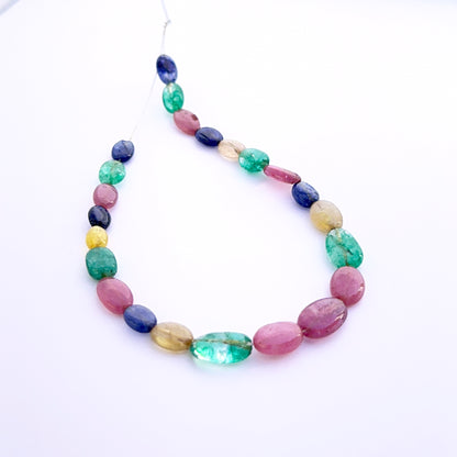Multi stone smooth oval beads 6–7mm featuring ruby, blue sapphire and emerald, 23 pieces totalling 45 carats.