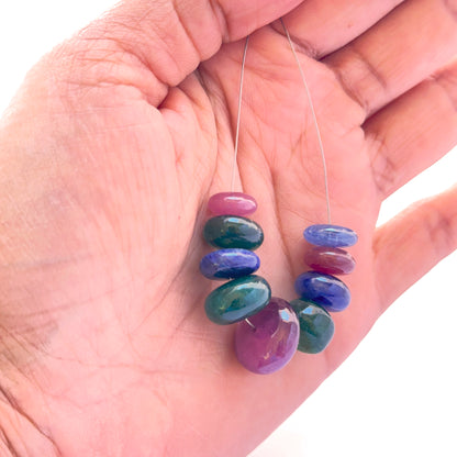 A person holds the multi stone smooth rondelle bead set, showcasing blue sapphire, ruby and emerald.
