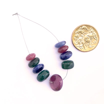 Smooth rondelle blue sapphire, ruby and emerald beads arranged to display uniform shape and rich gemstone colour.