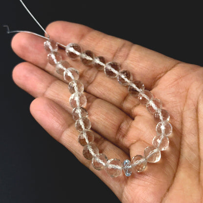 A person holds delicate strands of rose quartz and aquamarine beads, showcasing their faceted round design.