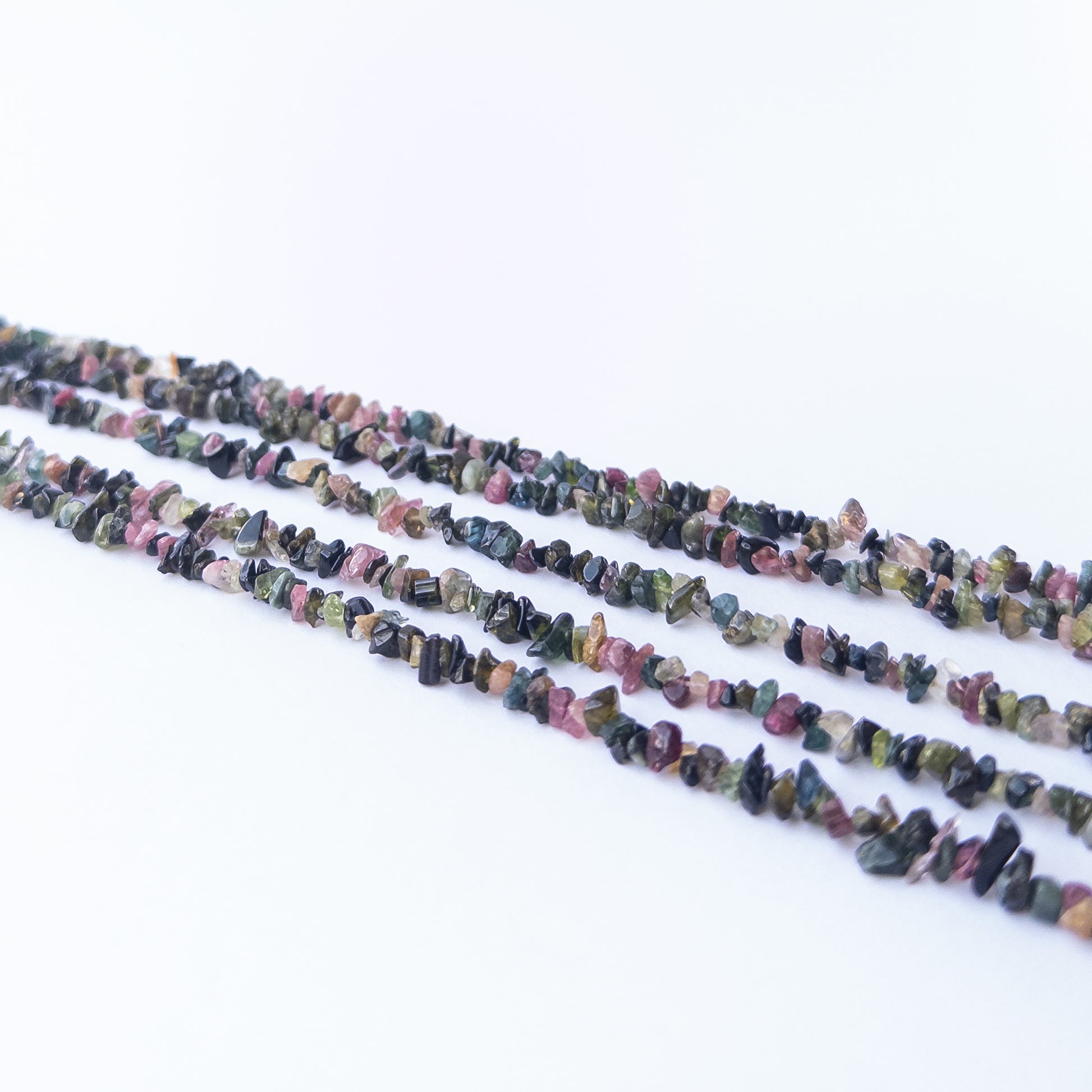 Multi Tourmaline chips arranged neatly, highlighting their colour variety and handcrafted bead quality.