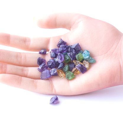 A person holds delicate pieces of Amethyst, Citrine, Apatite and Peridot rough, showcasing their natural design.