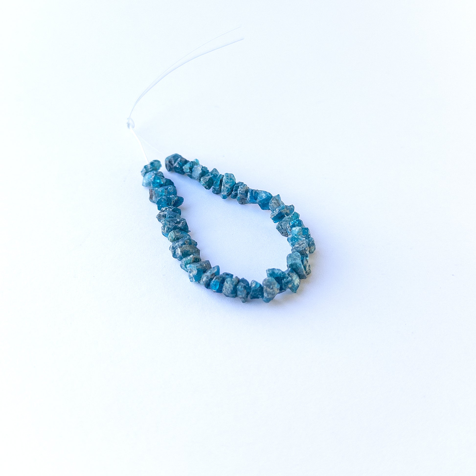 Neon Apatite drilled rough gemstone beads in vibrant blue tones arranged for handmade jewellery components.