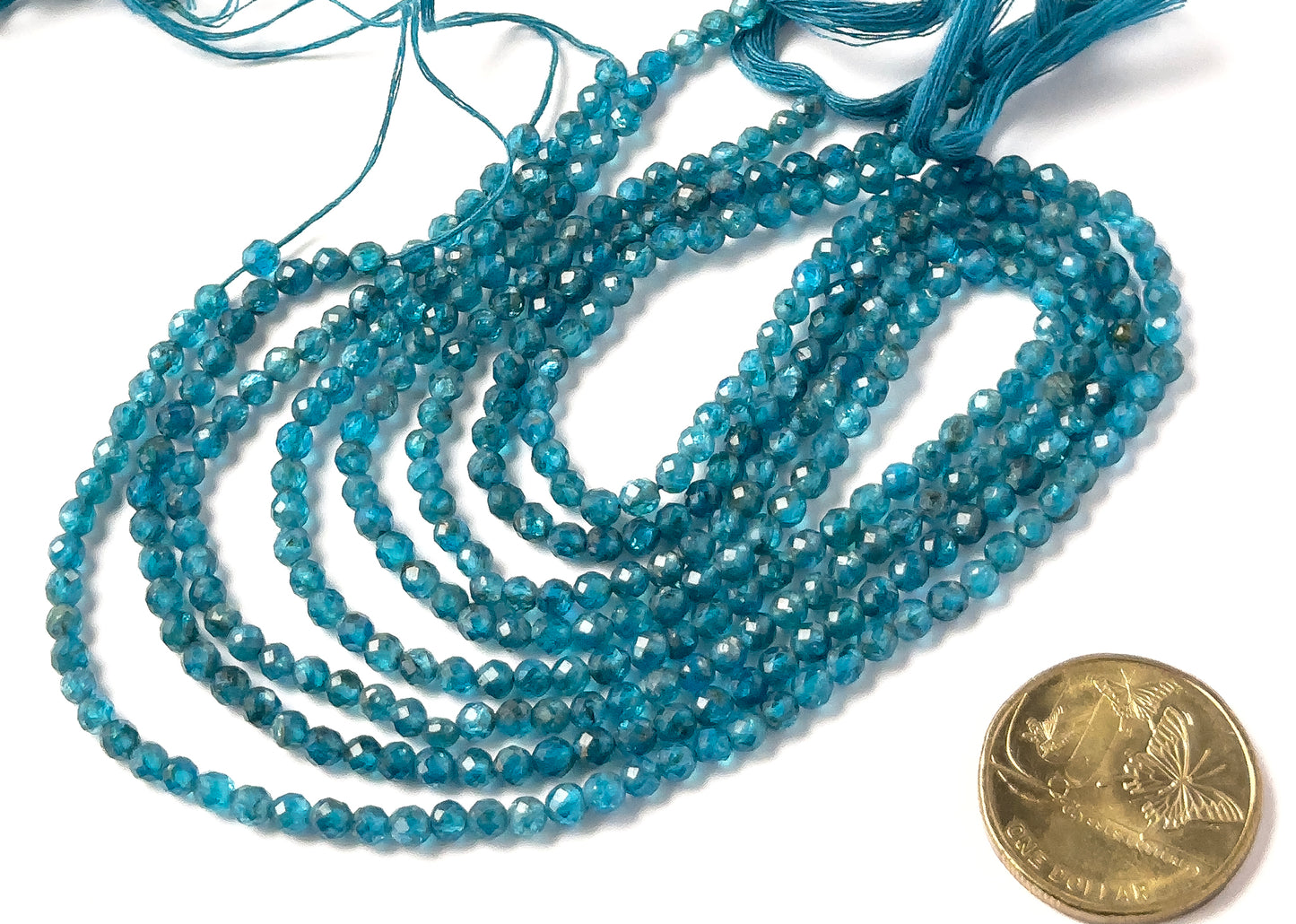 A coin is placed near Neon Apatite faceted rondelle beads to show the 3.5–3.7mm size range.
