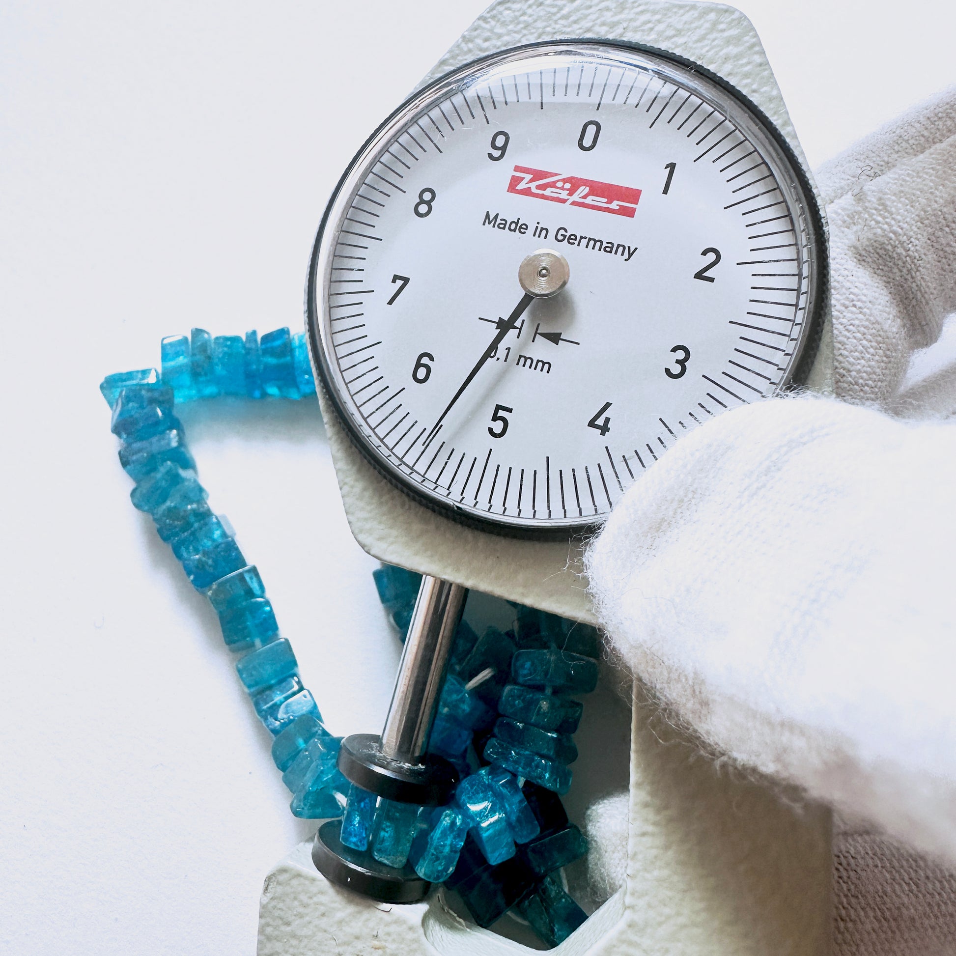A dial gauge measures the Neon Apatite square heishi 5-6mm gemstone.