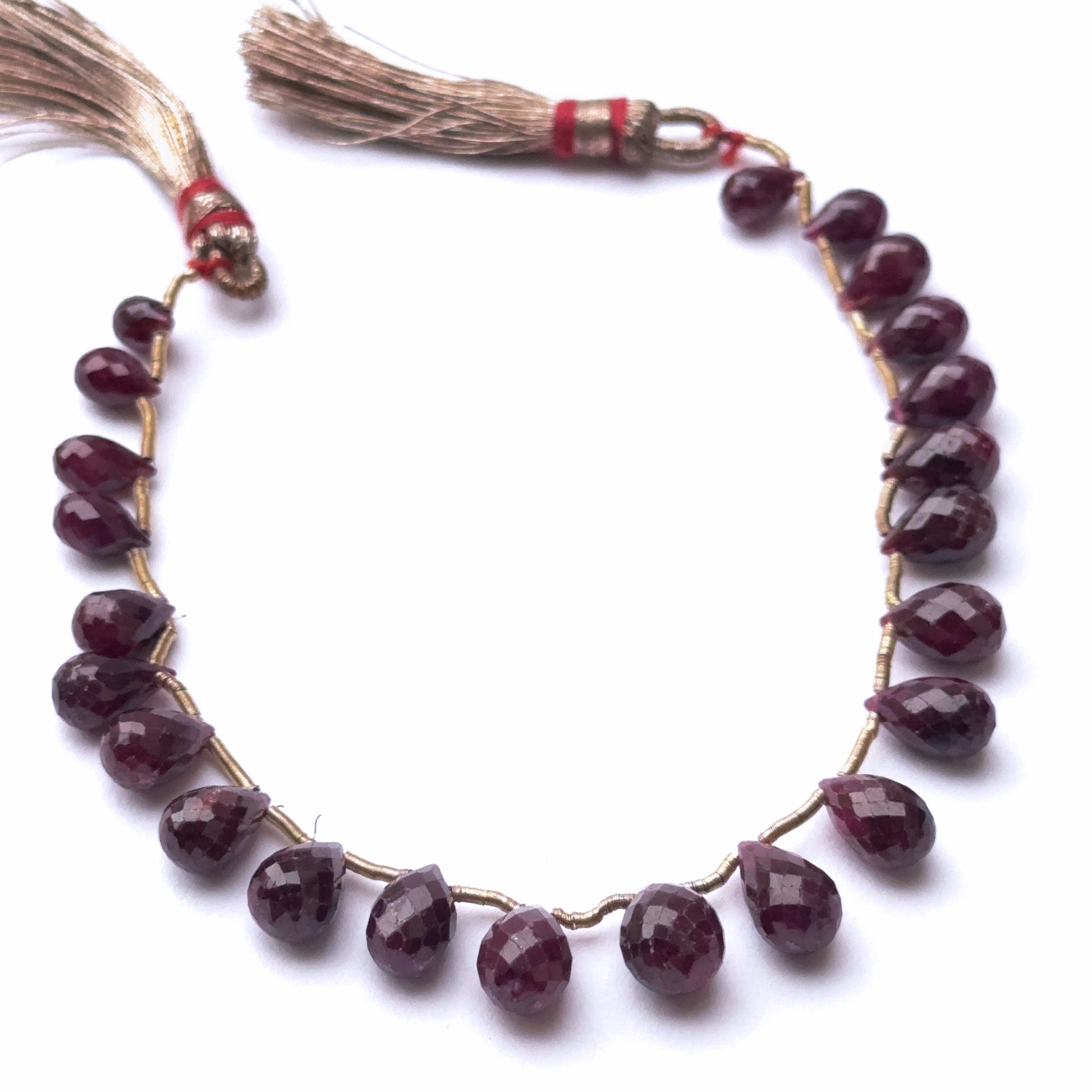 Close-up of gemstone beads showing ruby sparkle and teardrop shaping.