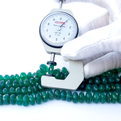 A dial gauge measures the Green Onyx Faceted Rondelle 9.5–10mm gemstone.