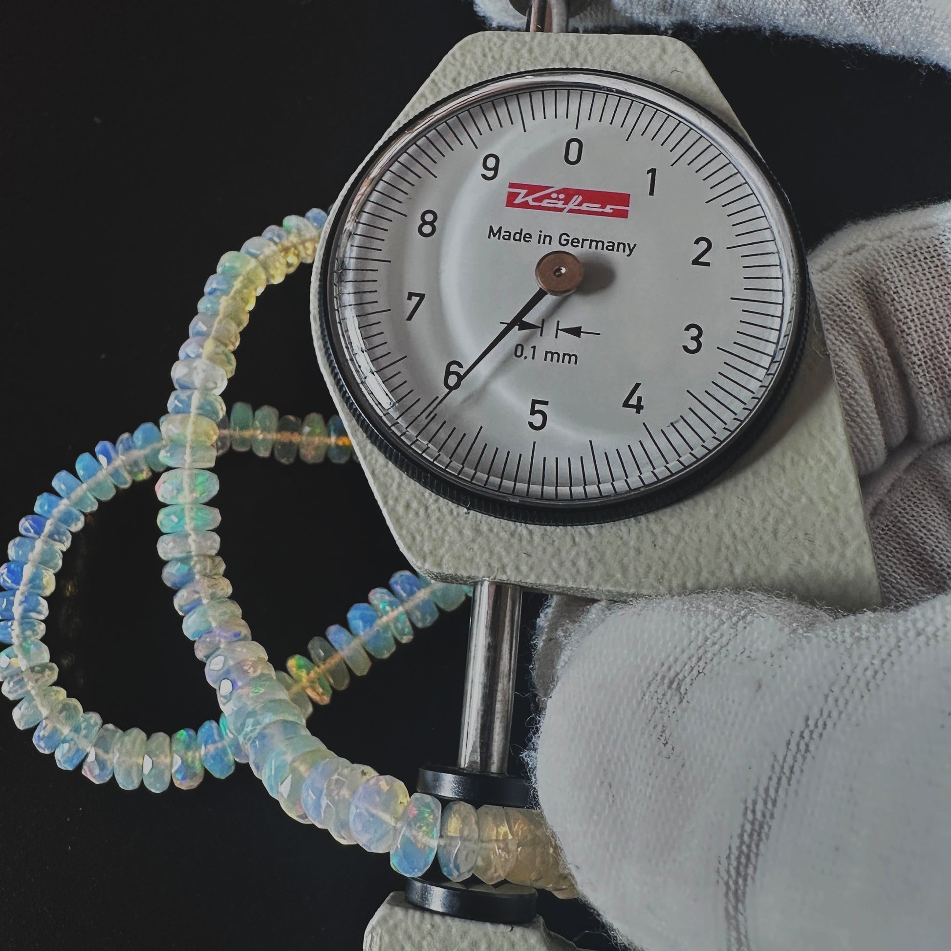 A dial gauge measures the Opal faceted rondelle 5.5-7.0mm gemstone.