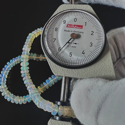 A dial gauge measures the Opal faceted rondelle 5.5-7.0mm gemstone.