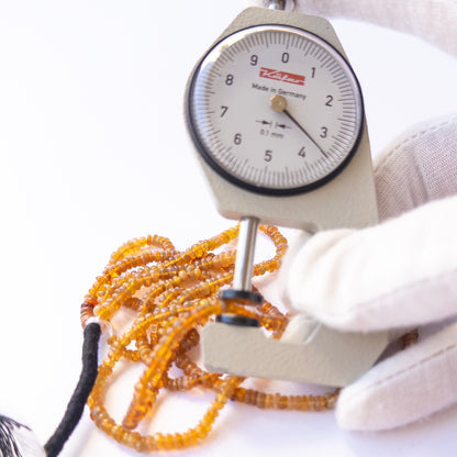 A dial gauge measures the Opal smooth rondelle 3.1–3.9mm gemstone.