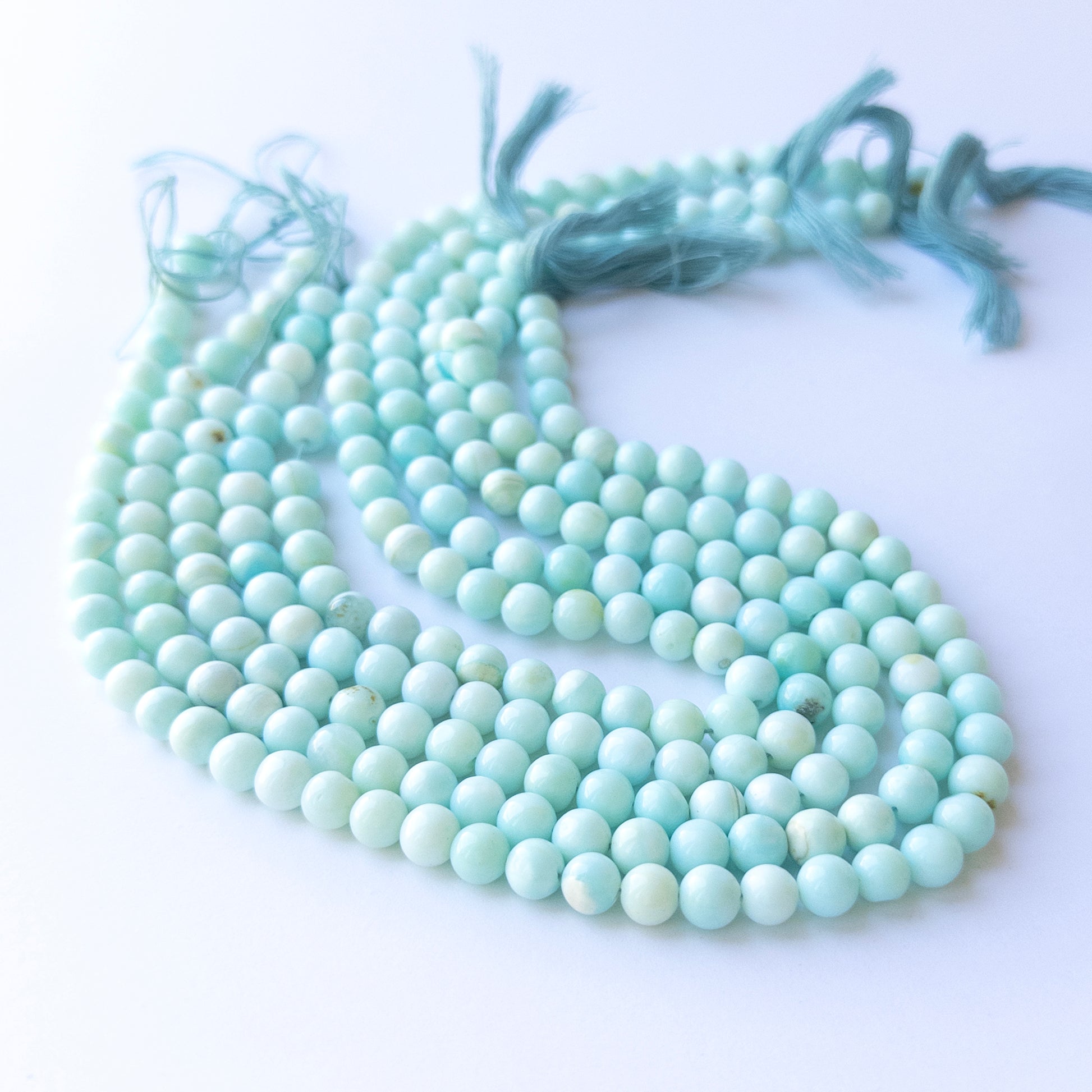 Genuine Opal gemstone beads displaying soft milky tones, polished surfaces, and a neatly arranged 31cm strand for jewellery design.