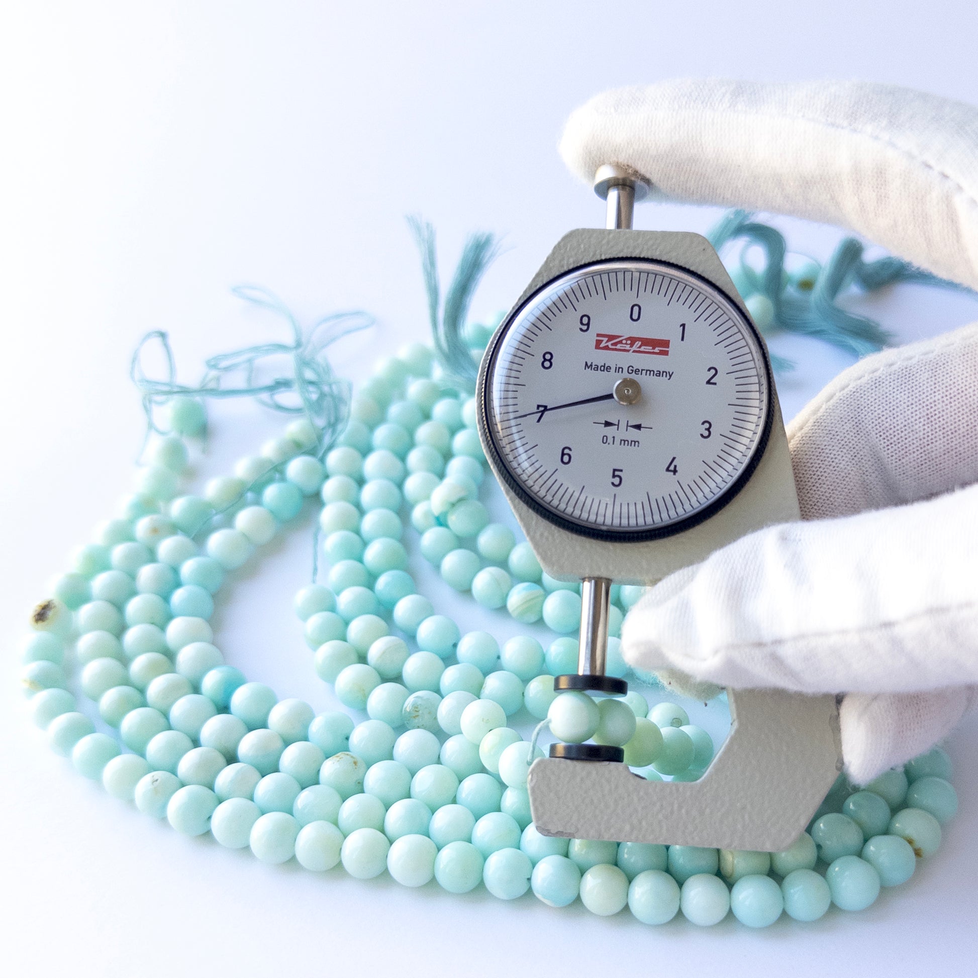 A dial gauge measures the Opal smooth round 6.8–7mm gemstone.