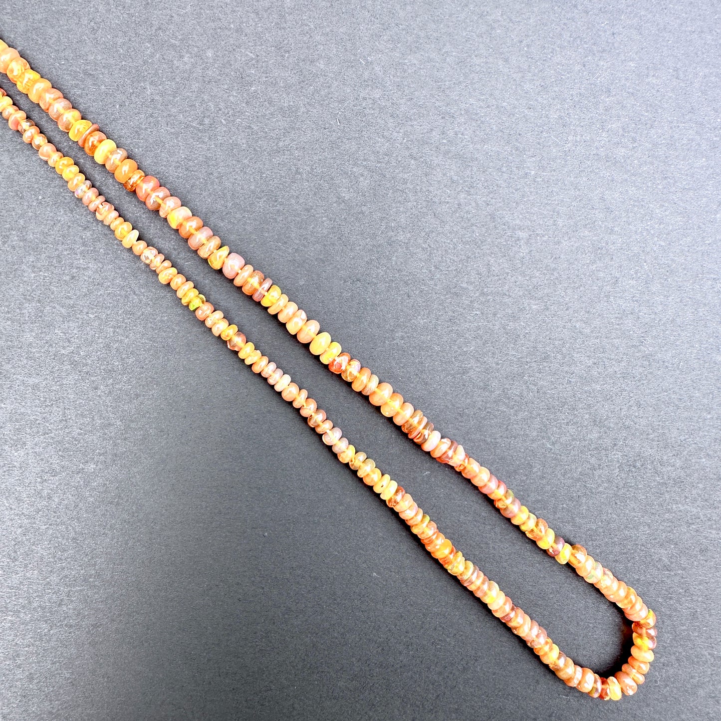 Opal with orange and yellow beads on a gray background.