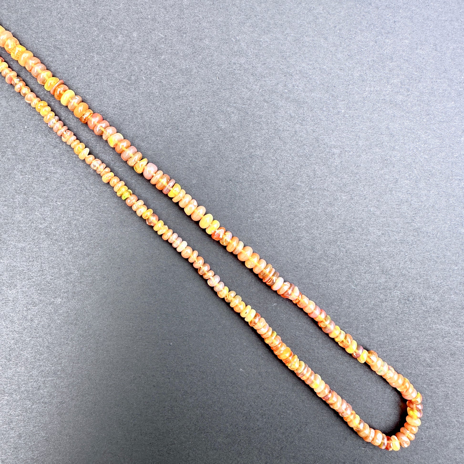 Opal with orange and yellow beads on a gray background.