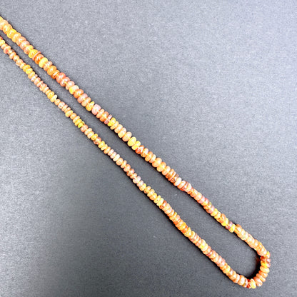 Opal with orange and yellow beads on a gray background.