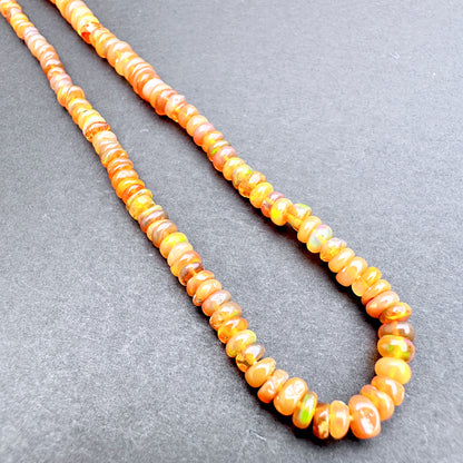 Opal with orange and yellow beads on a gray background.